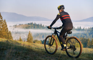smiling young man riding bicycle on mountain road.